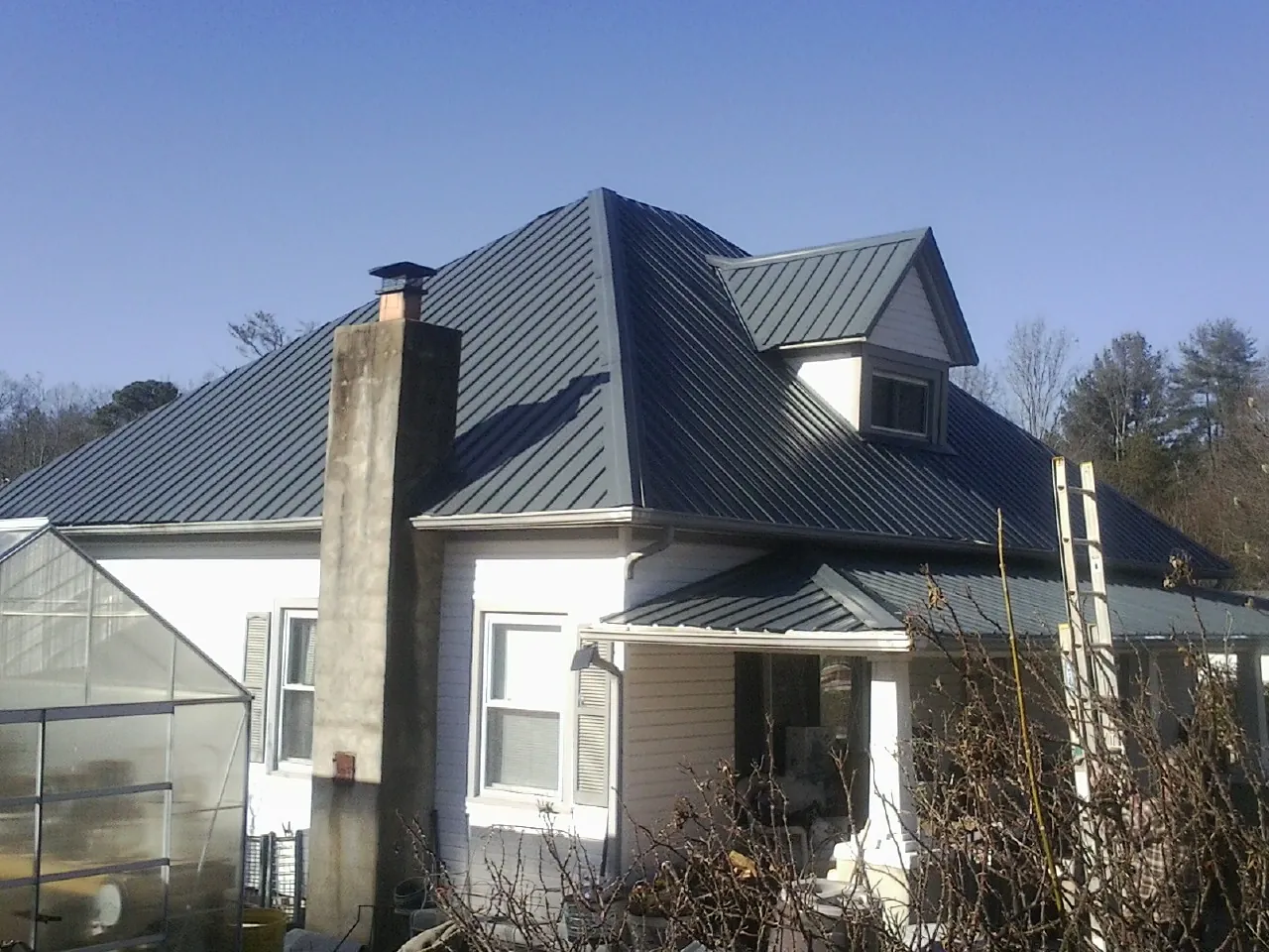 Dark blue standing seam metal roof on a white farmhouse with dormer — Slate & Tile Roof Repair by Roofing Brothers in Sauk Centre