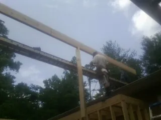 Carpenter setting a ridge beam over a new addition frame — Ice Dam Removal by Roofing Brothers in Sauk Centre