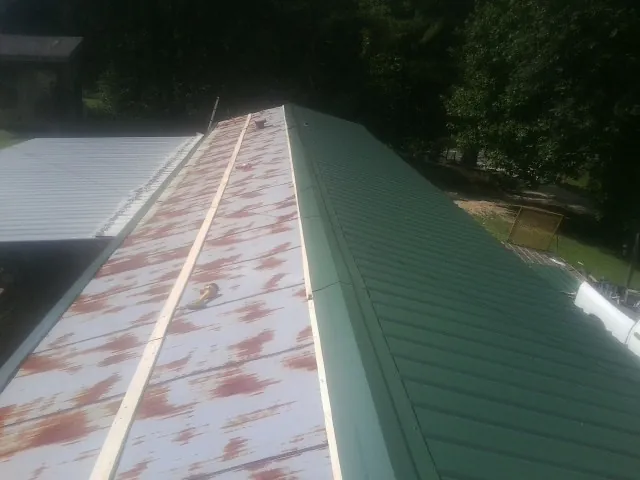 Old rusted panels beside newly installed green metal roofing — Wind Damage Roof Repair by Roofing Brothers in Sauk Centre