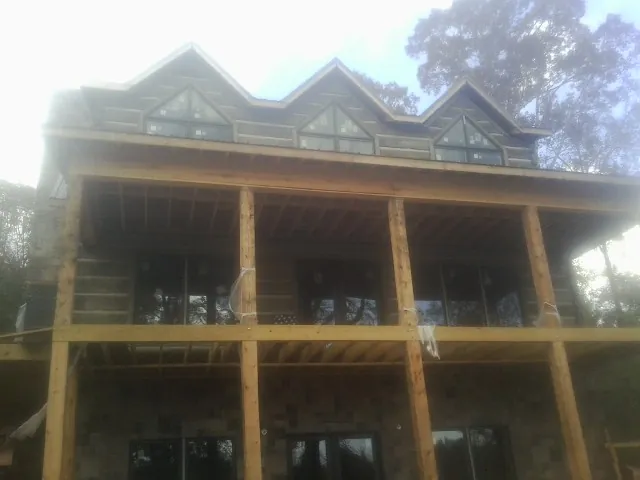 Dormers and porch framing on a large log home under construction — Roof Coating work by our crew in Sauk Centre