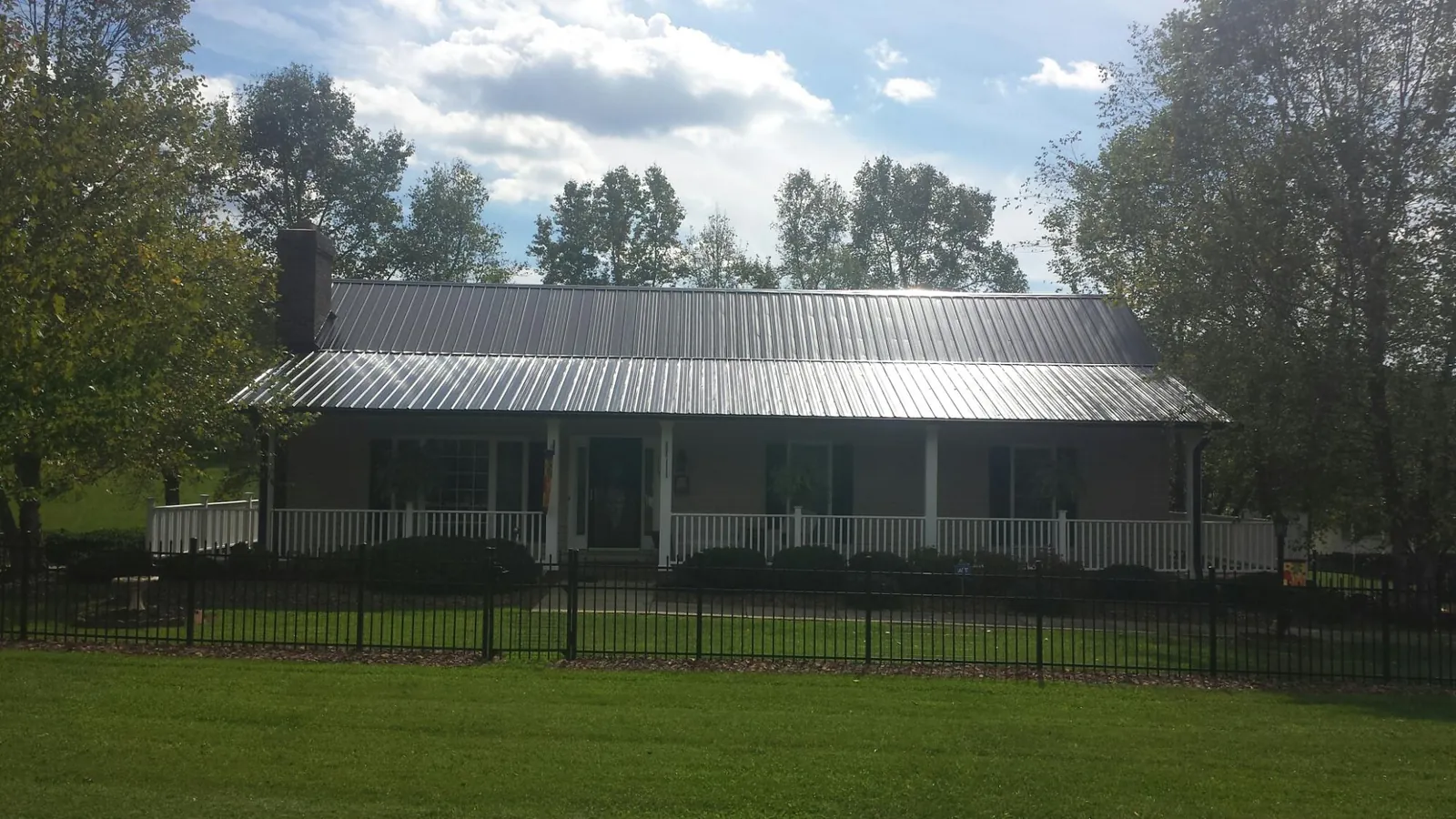 Gray metal roof on a brick ranch with a full width front porch — Gutter Guard Installation work by our crew in Sauk Centre